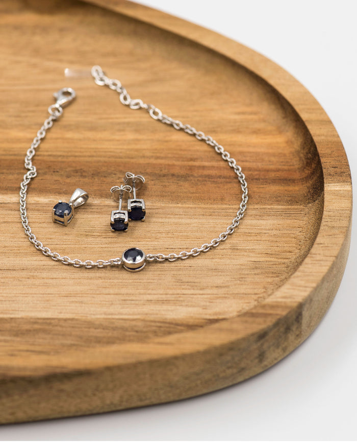 148 "Elegant silver 3-piece set, featuring round earrings with 50mm September sapphire stones, a matching pendant, and a bracelet with sapphire stones.