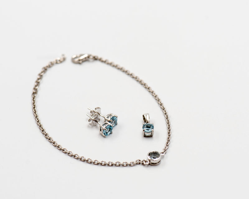 142 Elegant silver 3-piece set, featuring round earrings with 50mm March blue topaz stones, a matching pendant, and a bracelet with blue topaz stones.